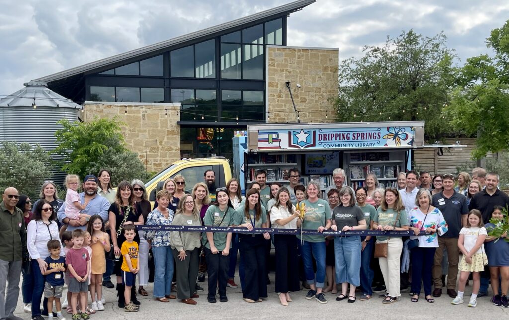 Ribbon cutting ceremony for Library on Wheels. Staff, board members, and sponsors standing in front of bookmobile.